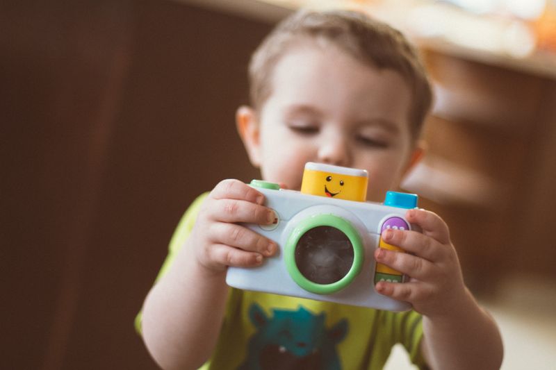 Bambino che tiene in mano una macchina fotografica giocattolo