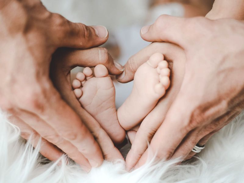 Piedini di neonato tra le mani dei genitori